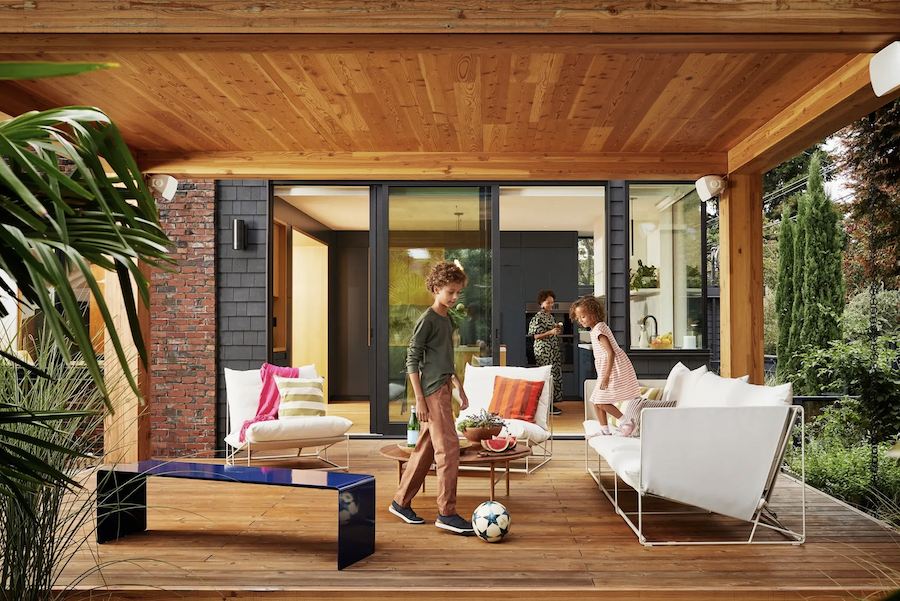 Two children play on a covered deck while Sonos outdoor speakers play music.