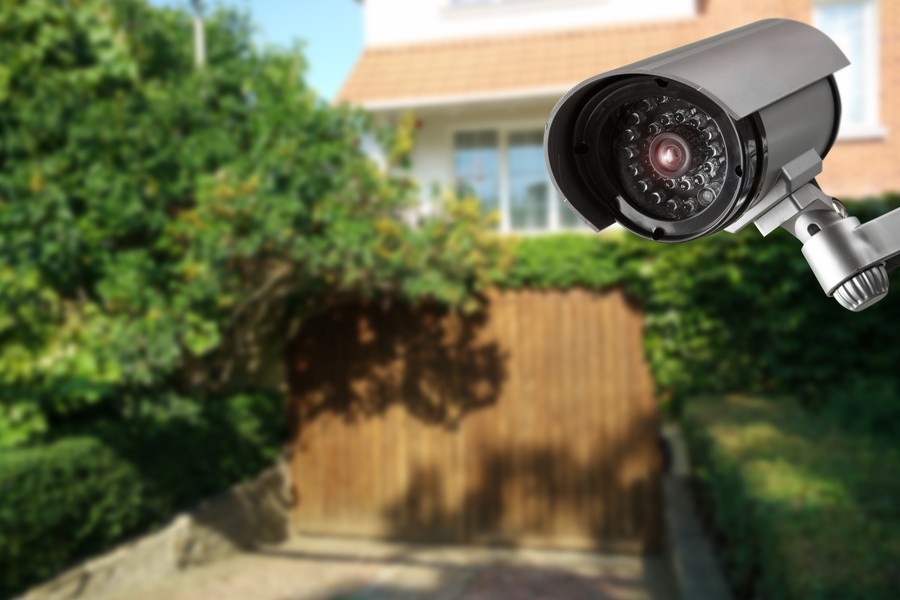 A video surveillance camera with a house in the background.